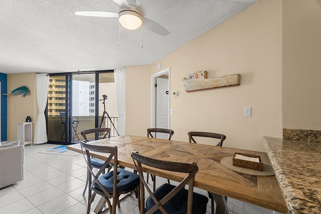 tiled dining room featuring ceiling fan, a wall of windows, and a textured ceiling