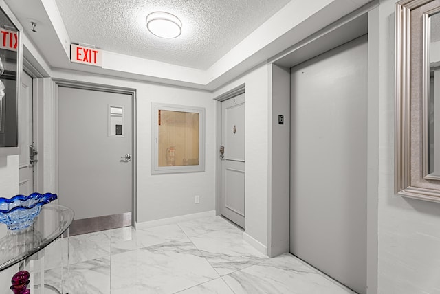 corridor with a textured ceiling and elevator