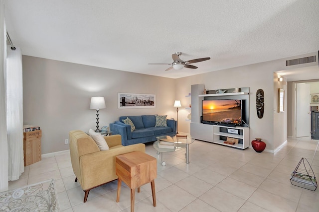 living room with light tile patterned flooring, ceiling fan, and a textured ceiling