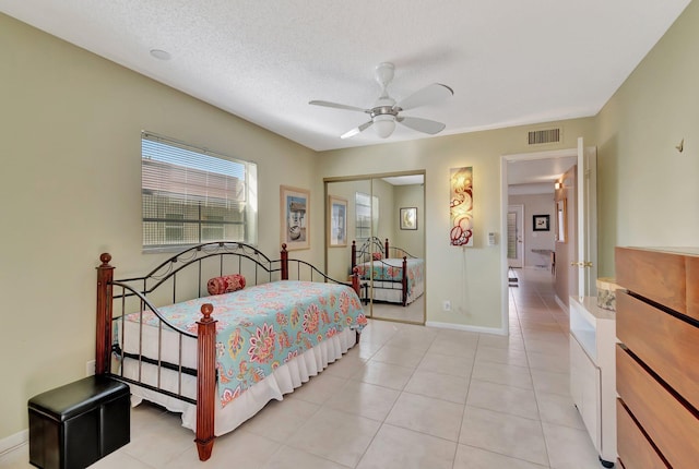 bedroom with light tile patterned floors, a textured ceiling, a closet, and ceiling fan