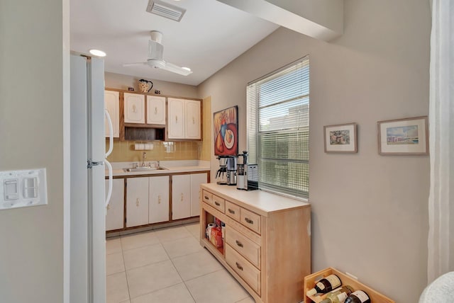 kitchen with sink, ceiling fan, tasteful backsplash, light tile patterned flooring, and white fridge