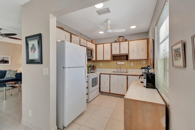 kitchen featuring sink, backsplash, light tile patterned floors, ceiling fan, and white appliances