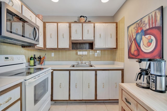 kitchen featuring light brown cabinetry, tasteful backsplash, sink, light tile patterned floors, and electric stove