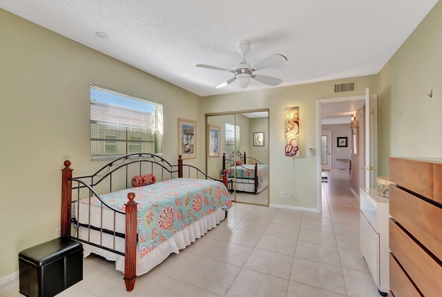 tiled bedroom featuring ceiling fan, a closet, and a textured ceiling