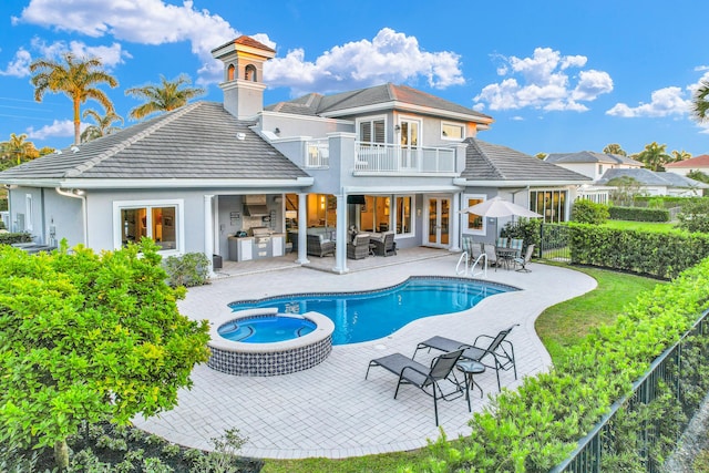 rear view of house featuring a balcony, an outdoor hangout area, a pool with connected hot tub, french doors, and a patio area