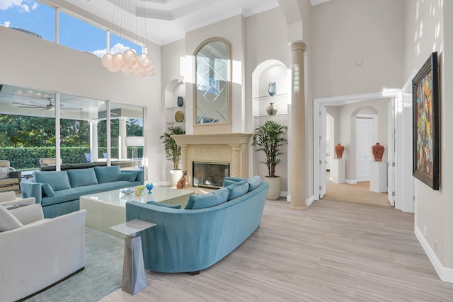 living area featuring crown molding, a fireplace, a high ceiling, ceiling fan, and wood finished floors