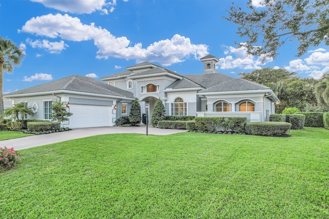 mediterranean / spanish house with an attached garage, concrete driveway, a front yard, and a tile roof