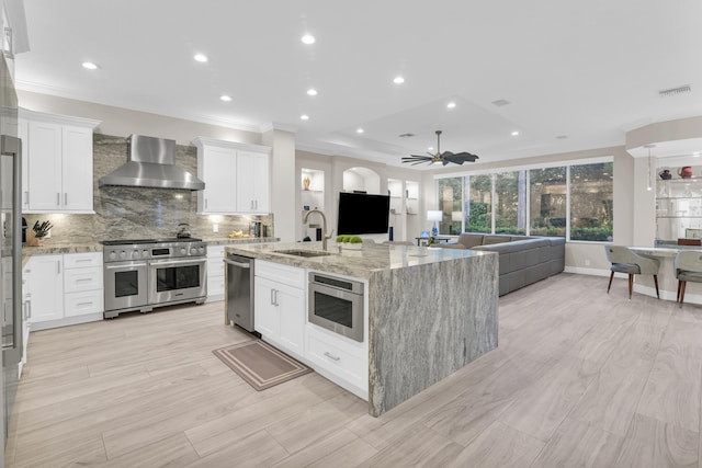 kitchen featuring white cabinetry, appliances with stainless steel finishes, sink, and wall chimney range hood