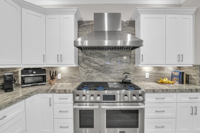 kitchen featuring a sink, visible vents, open floor plan, wall chimney range hood, and appliances with stainless steel finishes