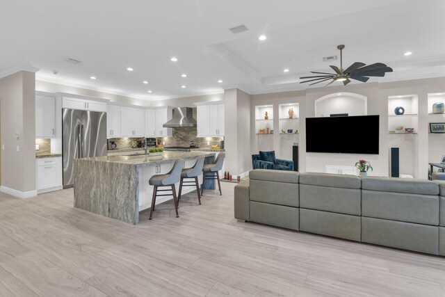 kitchen featuring white cabinetry, wall chimney range hood, and high end refrigerator