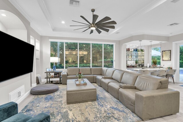 living room with crown molding, ceiling fan, and built in shelves