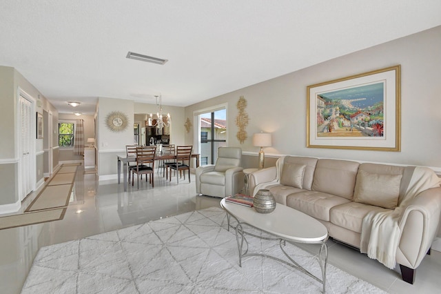 tiled living room featuring a healthy amount of sunlight and an inviting chandelier