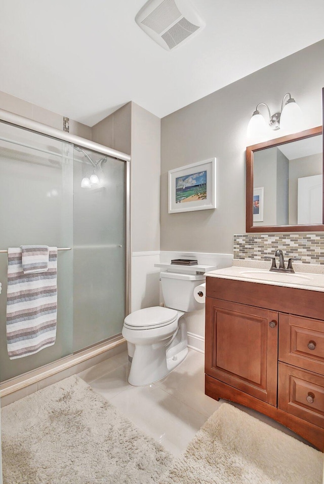 bathroom featuring backsplash, vanity, a shower with shower door, and toilet