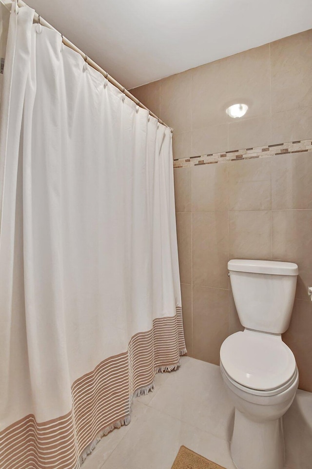 bathroom with tile patterned flooring, toilet, tile walls, and a shower with shower curtain