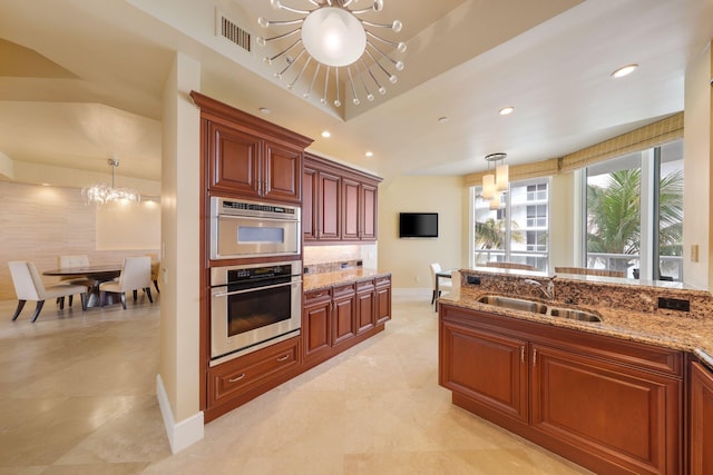 kitchen featuring light stone counters, a raised ceiling, sink, decorative light fixtures, and a chandelier