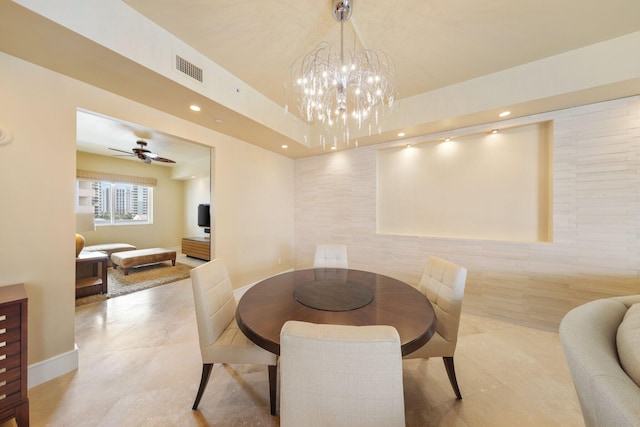 dining room with ceiling fan with notable chandelier, light tile patterned flooring, and tile walls