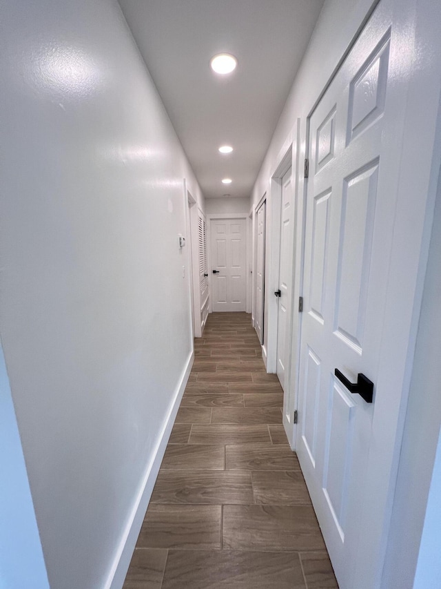 hall with dark wood-style floors, baseboards, and recessed lighting