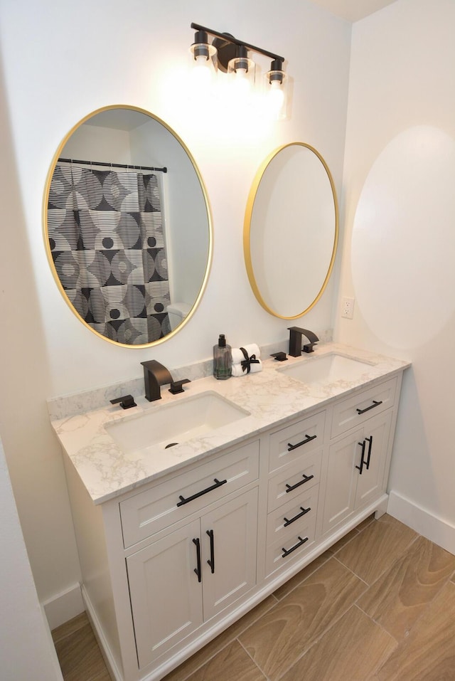 full bath with double vanity, a shower with curtain, a sink, and baseboards