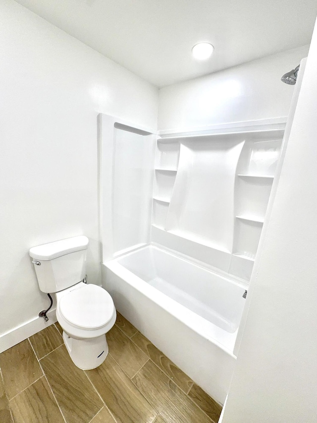 bathroom featuring toilet, shower / tub combination, baseboards, and wood finish floors