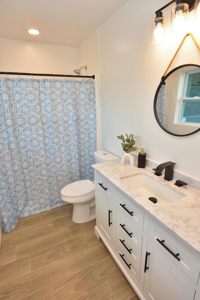 full bath featuring wood tiled floor, vanity, and toilet