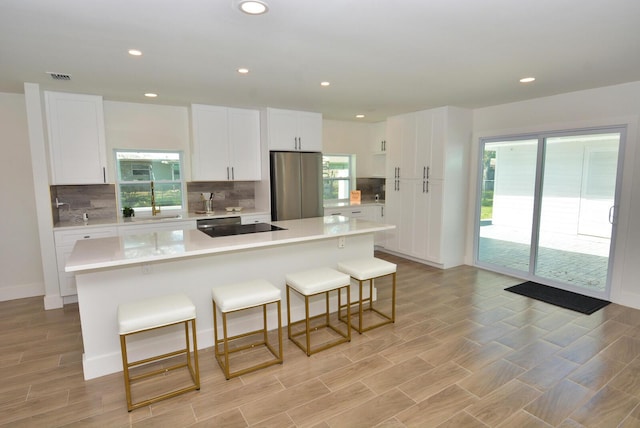 kitchen featuring light countertops, a kitchen island, freestanding refrigerator, and white cabinets