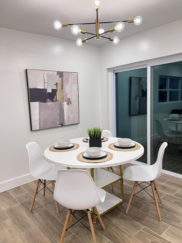 dining space featuring a chandelier, wood tiled floor, and baseboards