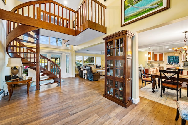 interior space featuring a high ceiling, ceiling fan with notable chandelier, light hardwood / wood-style floors, and crown molding