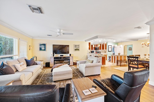 living room featuring crown molding, light hardwood / wood-style floors, and ceiling fan with notable chandelier