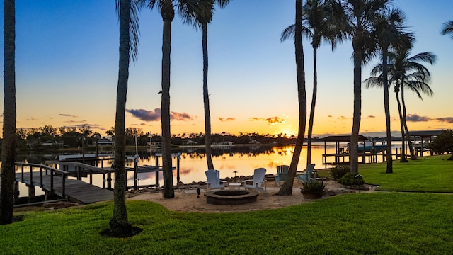 dock area featuring a lawn, a water view, and a fire pit