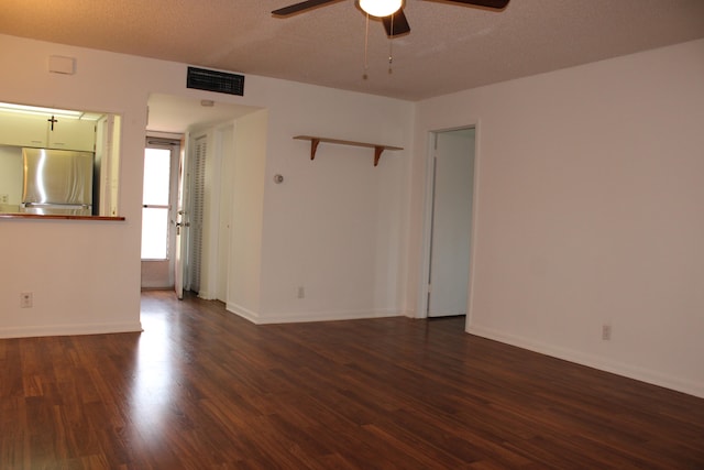 empty room featuring a textured ceiling, ceiling fan, and dark wood-type flooring