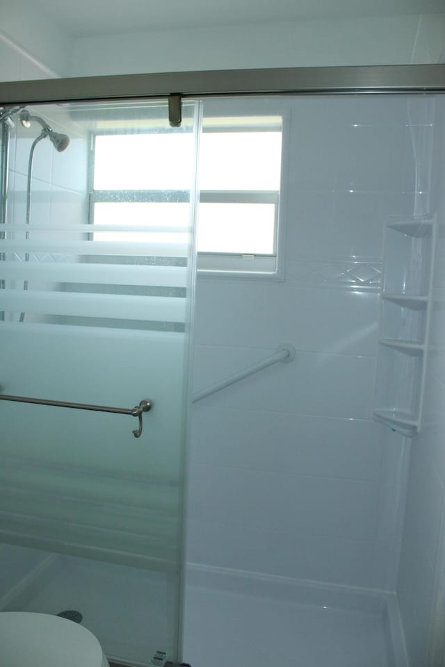 bathroom with tiled shower, a wealth of natural light, and toilet