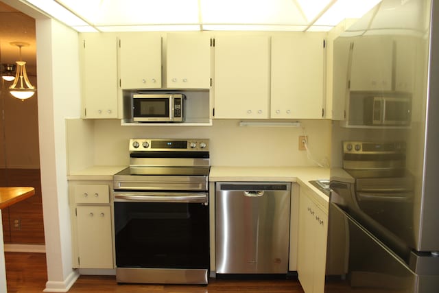 kitchen with white cabinets, decorative light fixtures, stainless steel appliances, and dark wood-type flooring