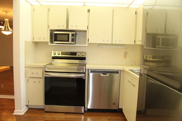 kitchen featuring pendant lighting, dark hardwood / wood-style flooring, white cabinetry, and appliances with stainless steel finishes