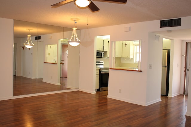 interior space featuring ceiling fan, dark wood-type flooring, pendant lighting, a textured ceiling, and appliances with stainless steel finishes