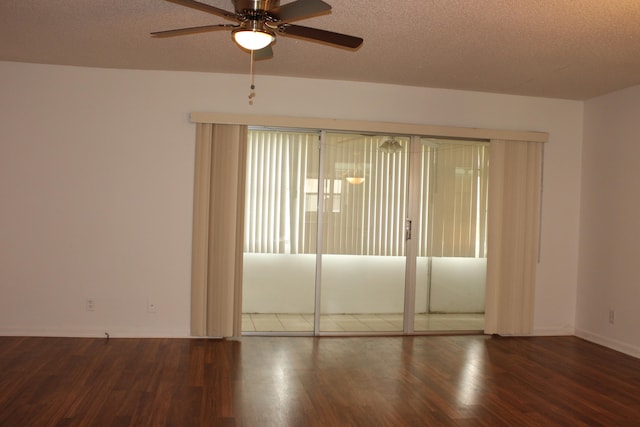 spare room with a textured ceiling, ceiling fan, and dark wood-type flooring