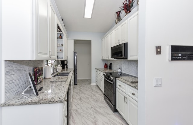 kitchen with sink, tasteful backsplash, light stone counters, white cabinets, and black appliances