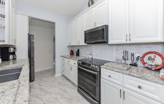 kitchen featuring light stone countertops, appliances with stainless steel finishes, tasteful backsplash, sink, and white cabinetry