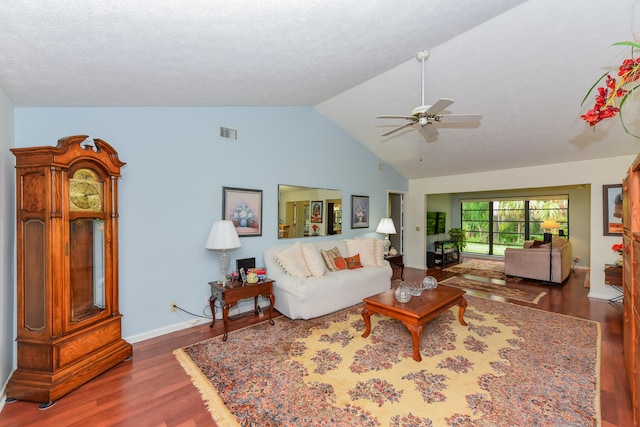 living room featuring a textured ceiling, ceiling fan, dark wood-type flooring, and vaulted ceiling