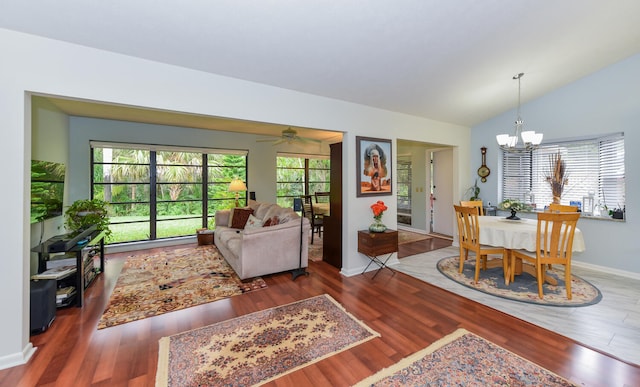 living room with ceiling fan with notable chandelier, dark hardwood / wood-style flooring, and vaulted ceiling