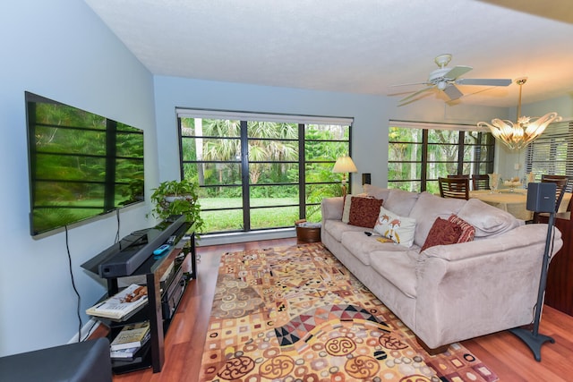 living room with ceiling fan with notable chandelier and hardwood / wood-style flooring