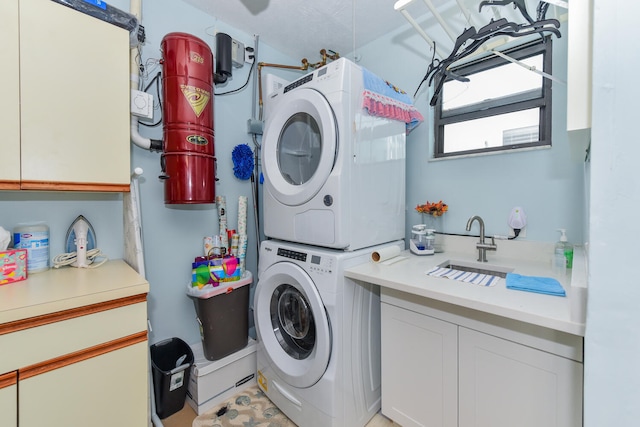 washroom featuring stacked washer / dryer, sink, and cabinets