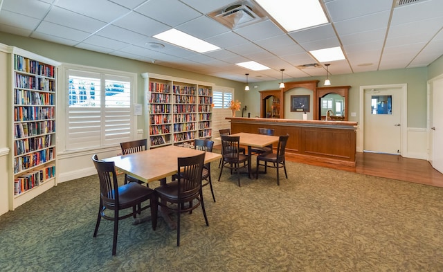 carpeted dining space featuring a drop ceiling