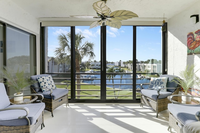 sunroom / solarium featuring ceiling fan and a water view