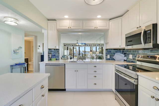 kitchen with white cabinetry, sink, stainless steel appliances, backsplash, and light tile patterned floors