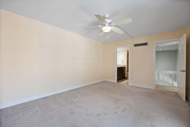 unfurnished bedroom with ceiling fan, light carpet, and ensuite bath