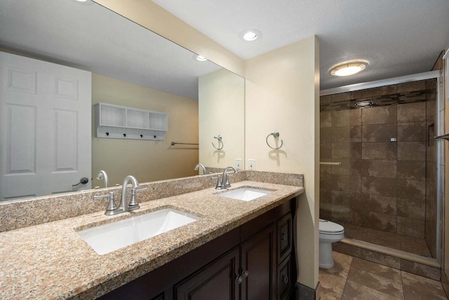 bathroom with tiled shower, vanity, and toilet