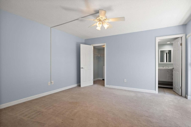 unfurnished bedroom with connected bathroom, ceiling fan, light colored carpet, and a textured ceiling