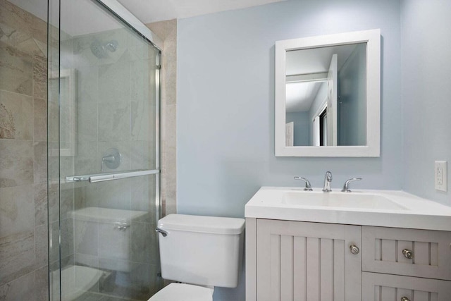 bathroom with a shower with door, vanity, and toilet