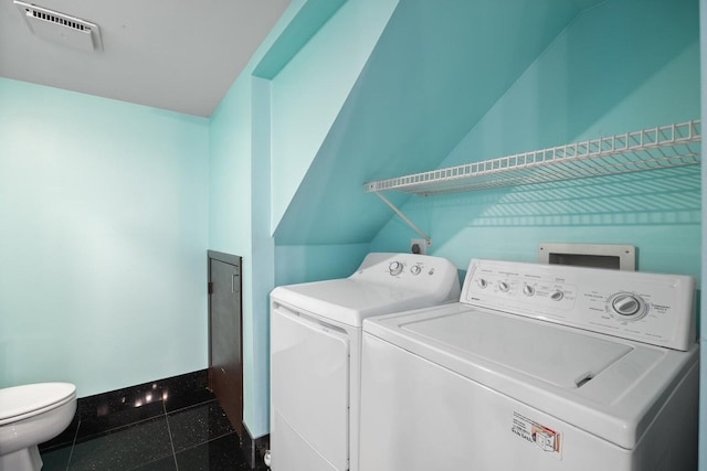 clothes washing area featuring washer and clothes dryer and dark tile patterned floors