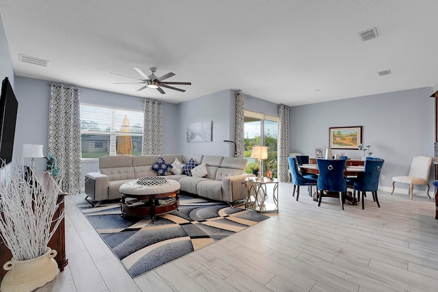 living room with light hardwood / wood-style flooring, ceiling fan, and a healthy amount of sunlight